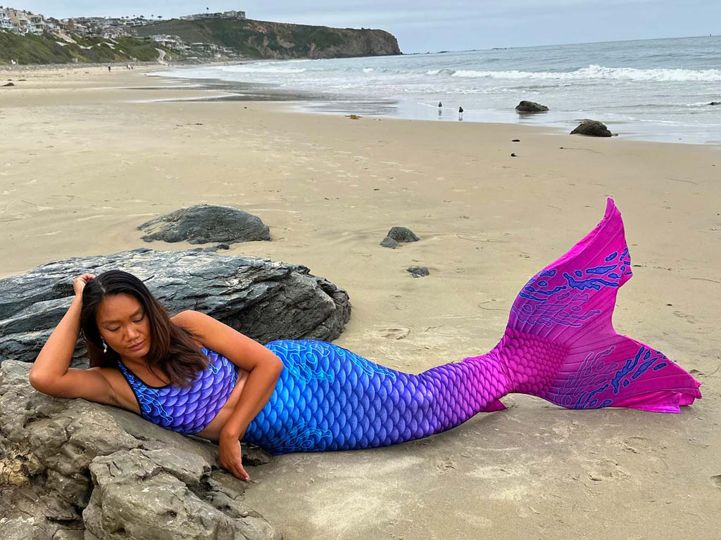Person wearing a colorful mermaid tail on a beach