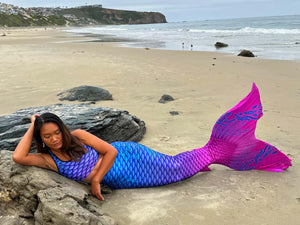 Person wearing a colorful mermaid tail on a beach
